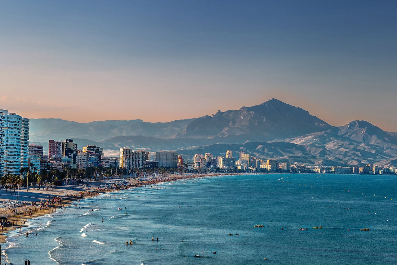 Stunning view of Alicante's beach and mountains at sunset.